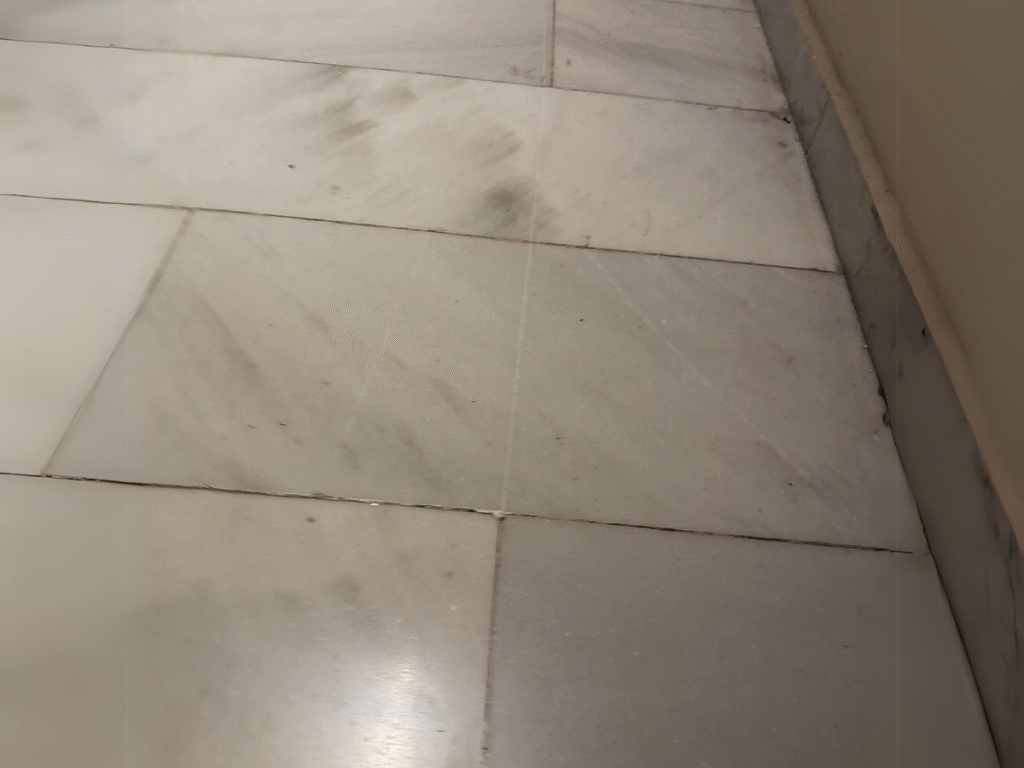 Piso de mármol blanco con rayaduras visibles y superficie opaca.